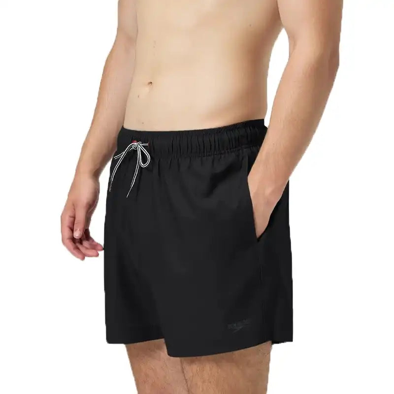 Profile of a man wearing black speedo board shorts