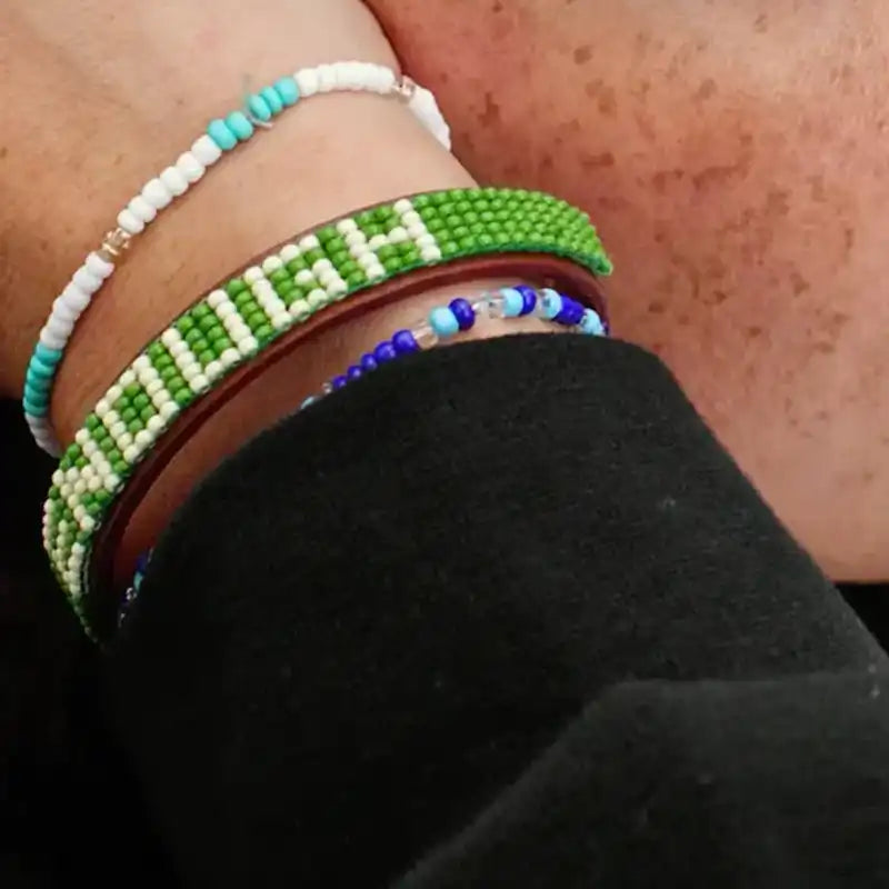 Close-up of a person's wrist wearing multiple beaded bracelets